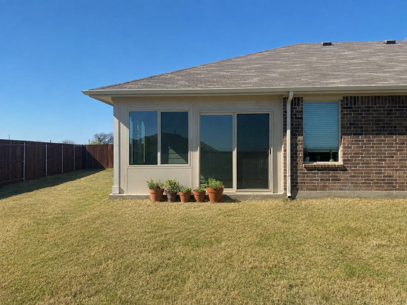 Tan glass sunroom addition on the corner of a brick home